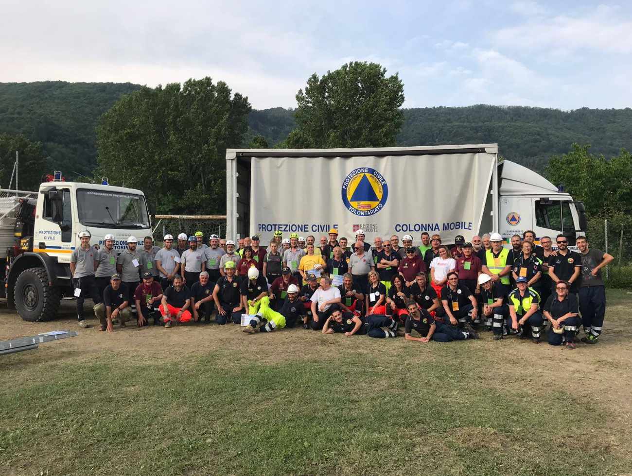 Gruppo di volontari Protezione Civile Torino davanti a mezzi operativi